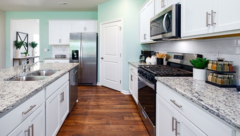model kitchen and island with white cabinets, wood floors and stainless steel appliances
