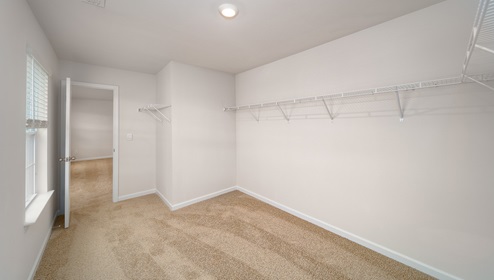Primary bedroom walk in closet with two windows