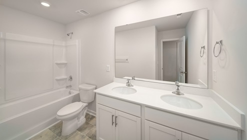 Bathroom with double sinks, white counters and cabinets, bathtub