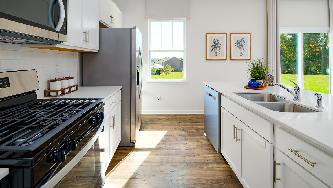 Kitchen with island, white cabinets, vinyl floors, and stainless steel appliances