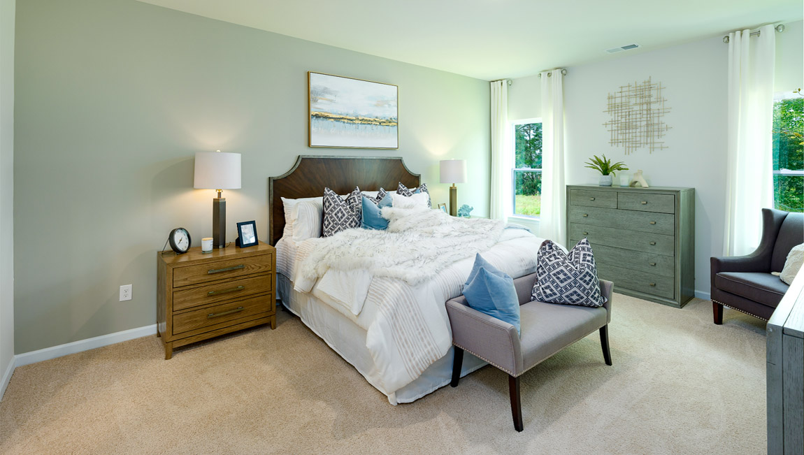 Carpeted primary bedroom with two small windows