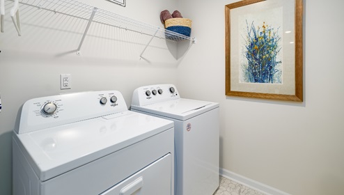 Laundry room with racks above machines for hanging and storage