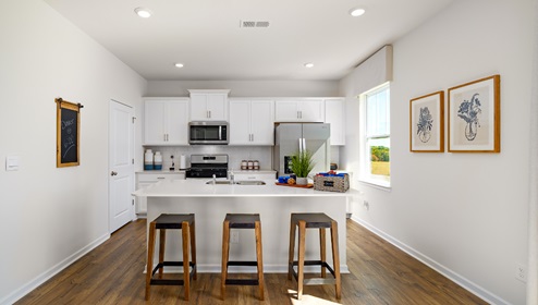 Kitchen with island, white cabinets, vinyl floors, and stainless steel appliances
