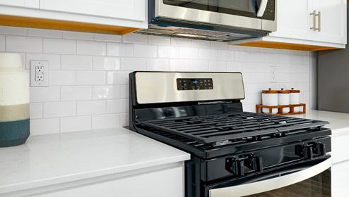 Kitchen with island, white cabinets, vinyl floors, and stainless steel appliances