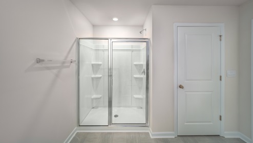 Primary bathroom with double sinks, white cabinets and glass door shower