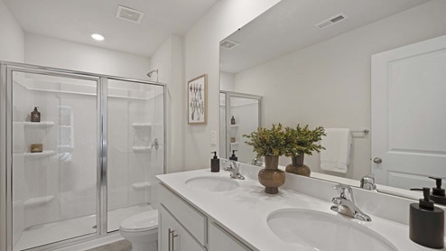 Bathroom with double sink vanity, and standing glass door shower