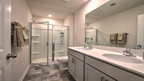 Bathroom with white cabinets and counters, glass door shower