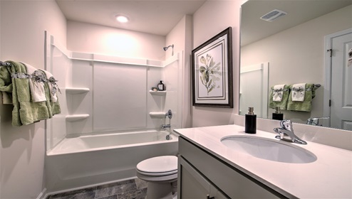 Bathroom with bathtub, white cabinets and counters