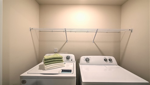 Laundry room with rack above machines