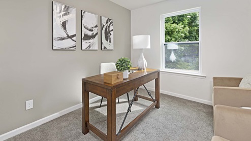 Carpeted bedroom with small window being used as an office