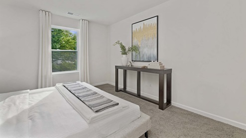 Carpeted primary bedroom with small window