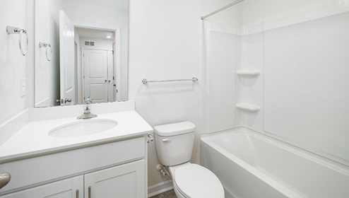 bathroom with white cabinets and counters, with a bathtub