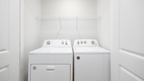 Laundry room with storage racks above machines