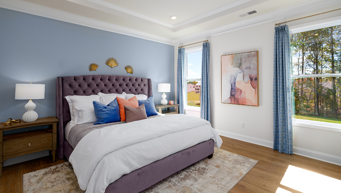 Primary bedroom with wood floors, and two large windows