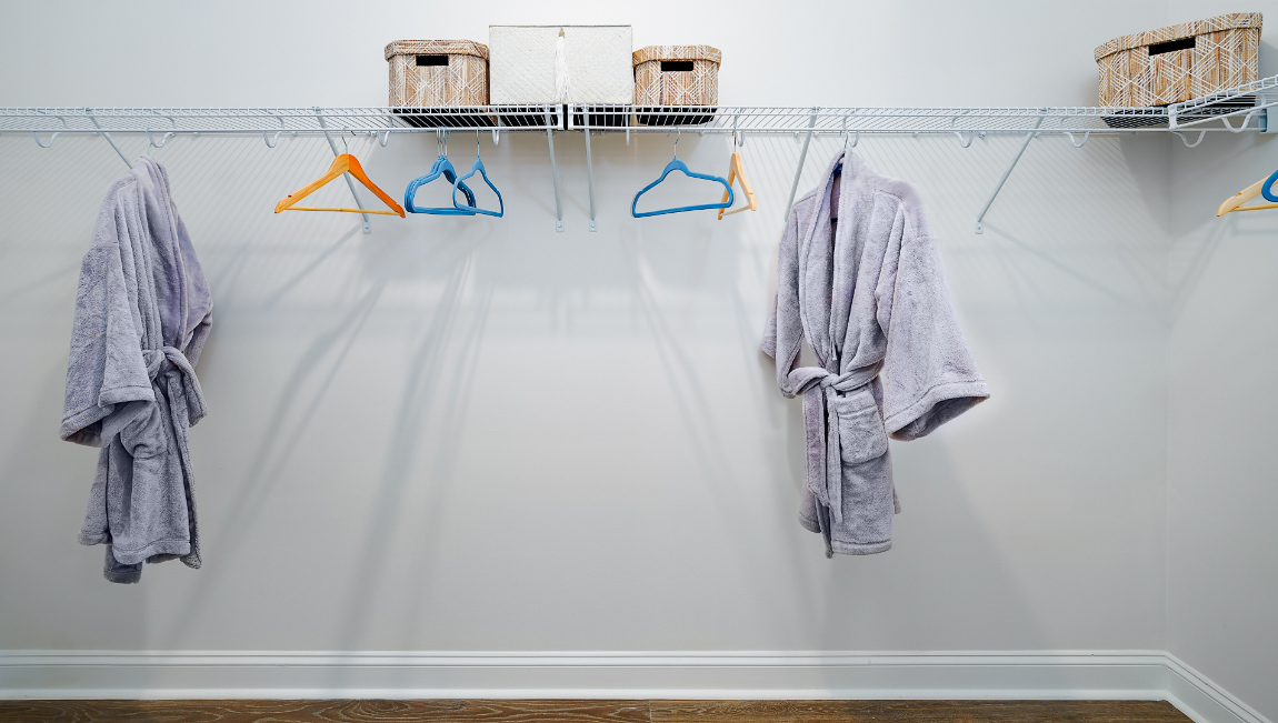 Primary bedroom walk in closet with wood floors and racks for hanging