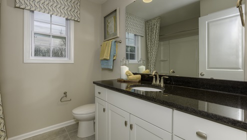 Bathroom with double sinks, white cabinets and bathtub