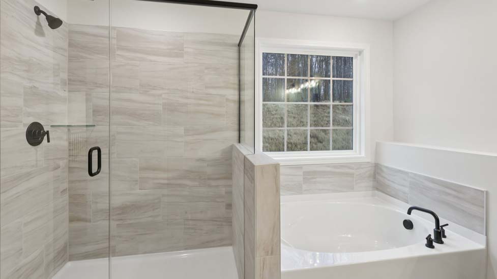 Primary bathroom with double sinks and tub with standing glass shower