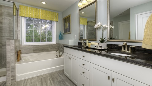 Primary bathroom with white cabinets, bathtub, and glass door shower