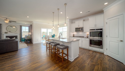Kitchen and island with wood floors, white cabinets, breakfast area on island bar, and stainless steel appliances