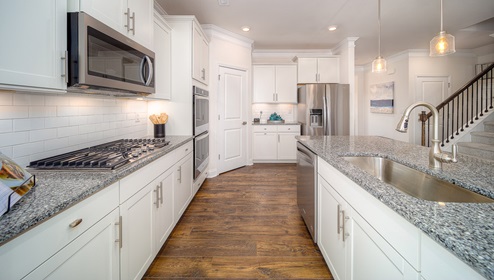 Kitchen and island with wood floors, white cabinets, breakfast area on island bar, and stainless steel appliances