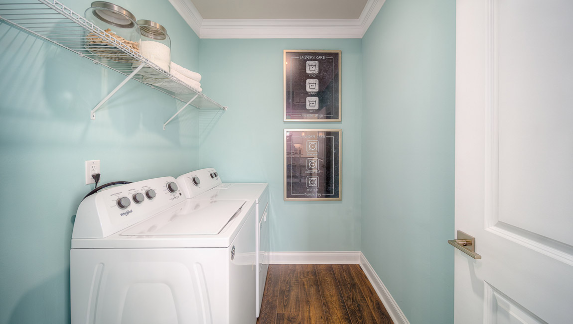 Laundry room with racks above machines for storage and hanging