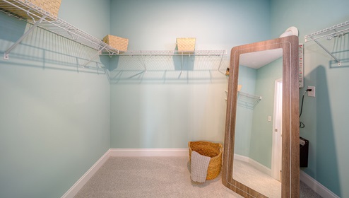 Primary bedroom walk in closet with built in racks for hanging