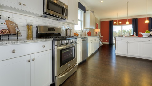 Kitchen and island with white cabinets, breakfast area at island bar, and stainless steel appliances