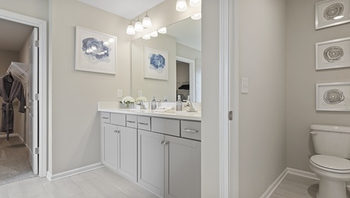 Bathroom with double sinks, white cabinets and counters