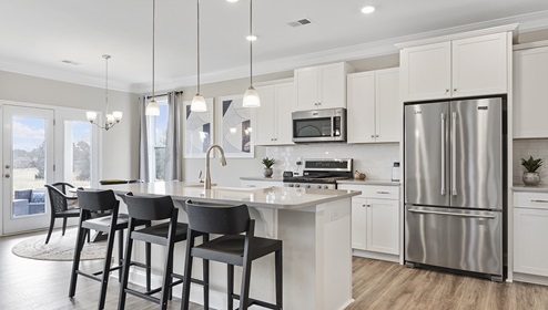 Kitchen and island with white cabinets and counters, wood floors, and stainless steel appliances