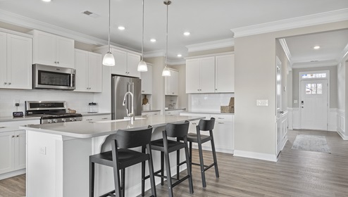 Kitchen and island with white cabinets and counters, wood floors, and stainless steel appliances