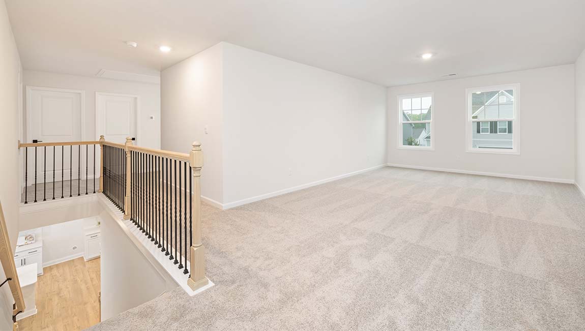Carpeted upstairs loft with large windows