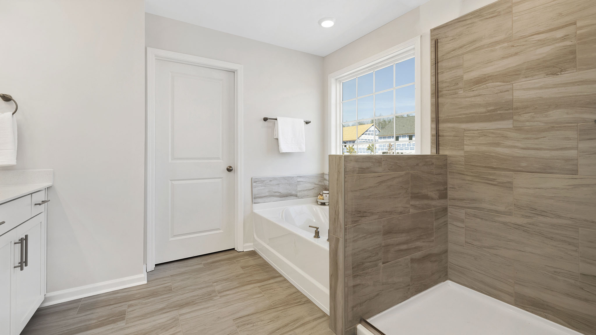 Primary bathroom with large window, bath, and standing shower