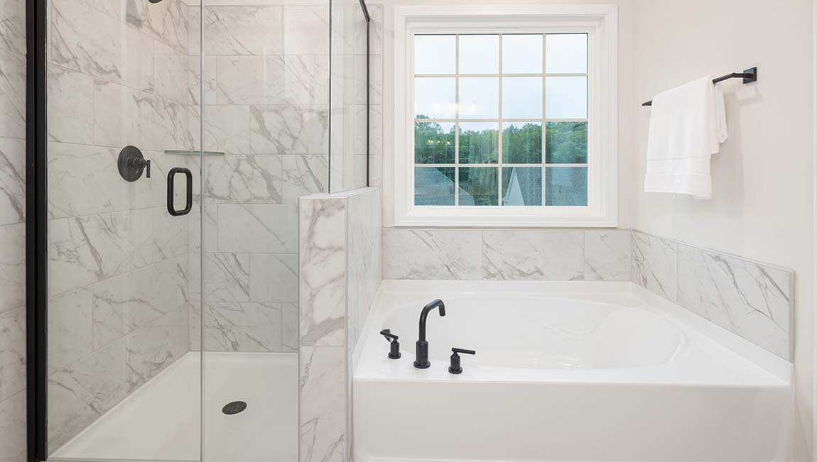 Primary bathroom with large window, bath, and standing shower