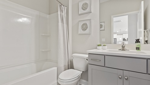 Bathroom with grey cabinets and white counters, and bathtub