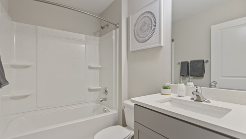Bathroom with grey cabinets and white counters, and bathtub