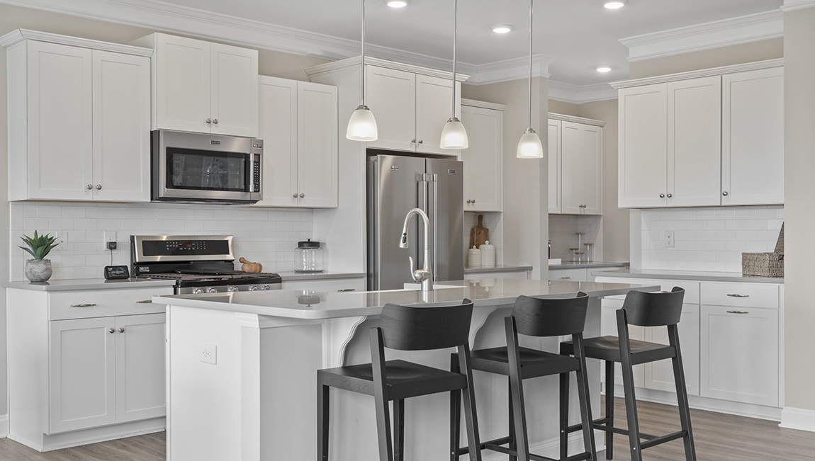 Kitchen and island with white cabinets and counters, wood floors, and stainless steel appliances