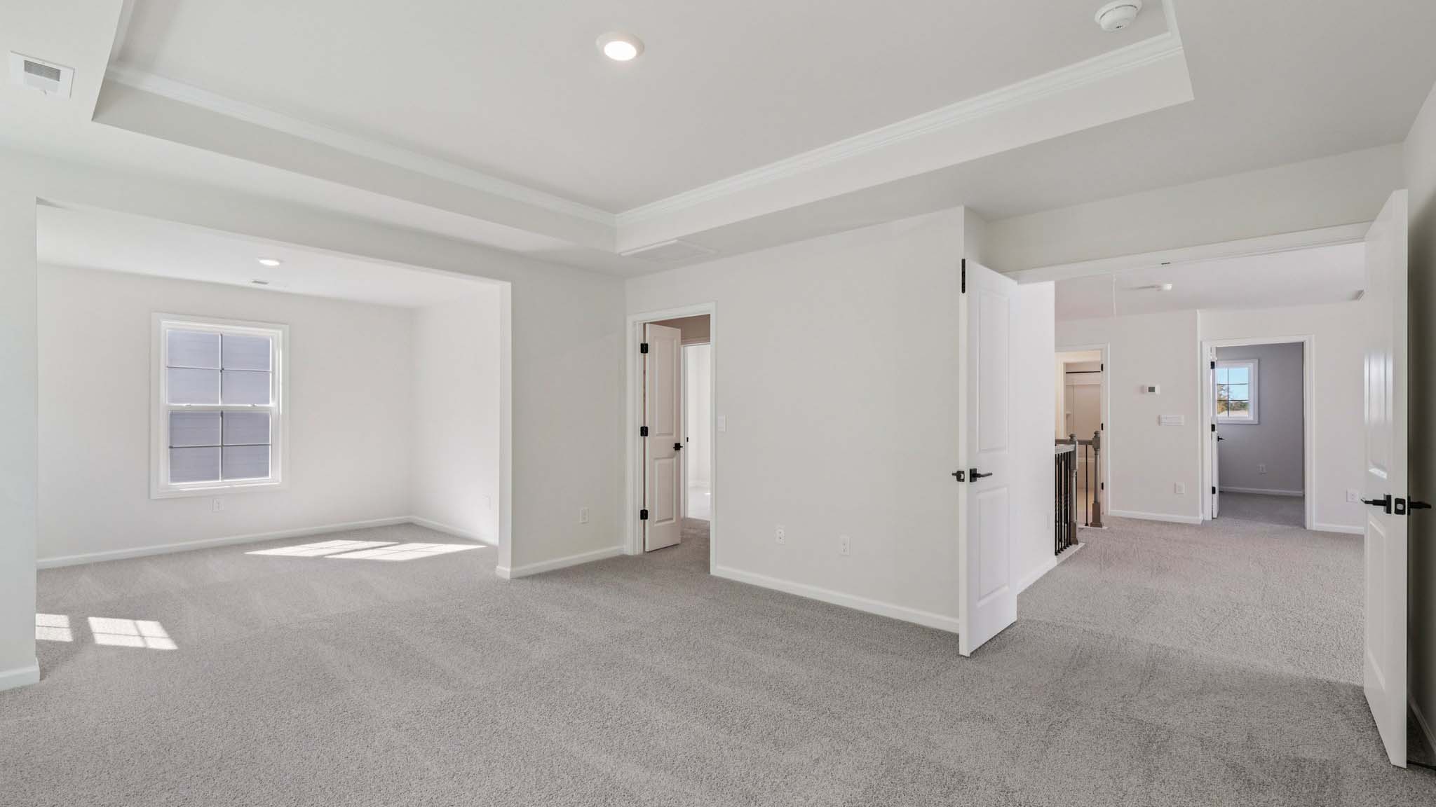Primary carpeted bedroom with large windows