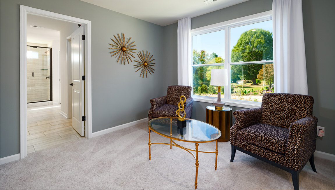 Carpeted sitting room in primary bedroom, with large window