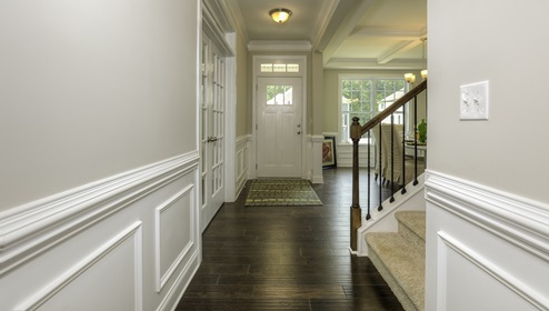 Welcoming foyer with wood floors, and view of staircase, front door and dining room