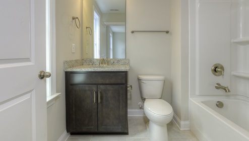Bathroom with brown cabinets and bathtub