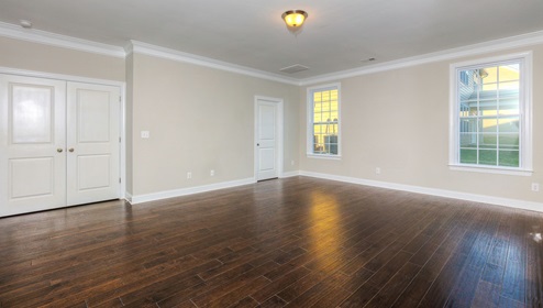 Primary bedroom with wood floors, large windows and large double doors at entrance