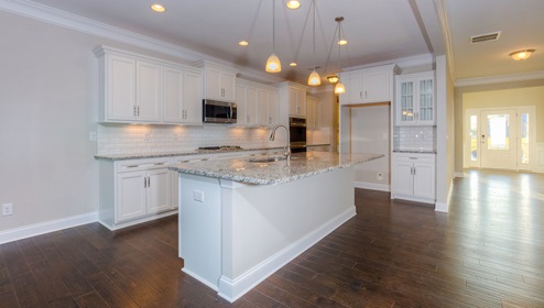 Kitchen and island with white cabinets, subway tile backsplash, and stainless steel appliances