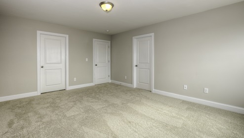 Carpeted bedroom with view of entryway doors and closet