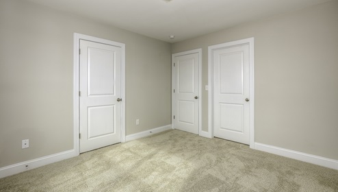 Carpeted bedroom with view of entryway doors and closet
