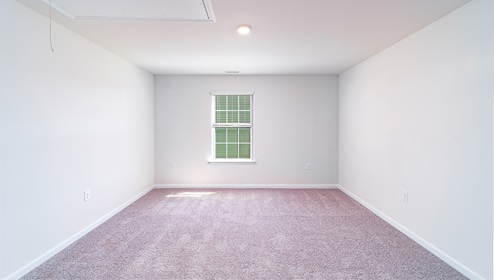 Carpeted loft space with small window