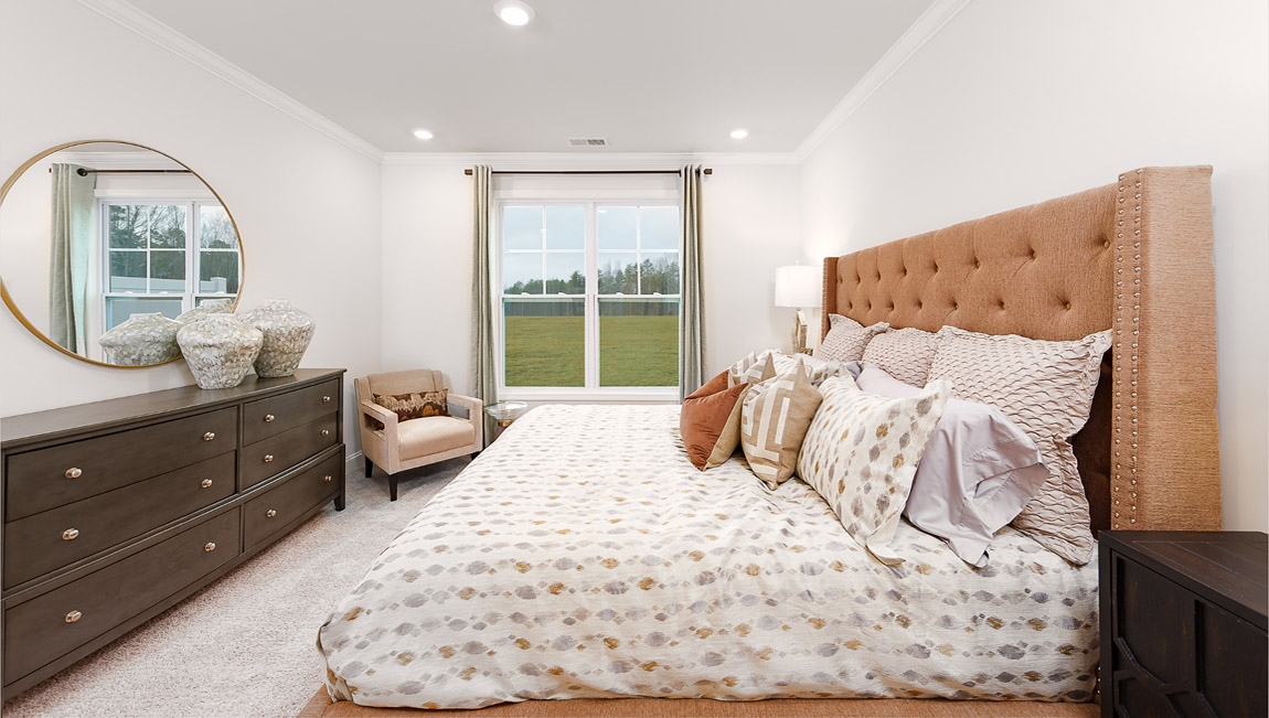 Primary suite with hardwood floors and large window