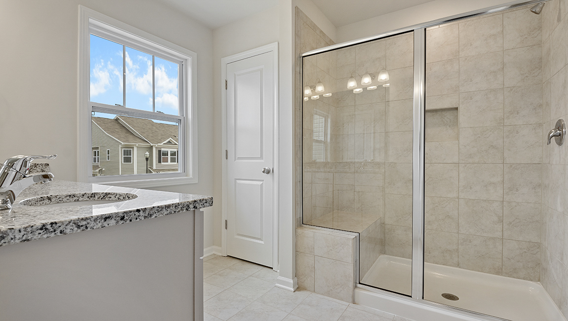 Primary bathroom with double sink vanity, walk in shower and bench