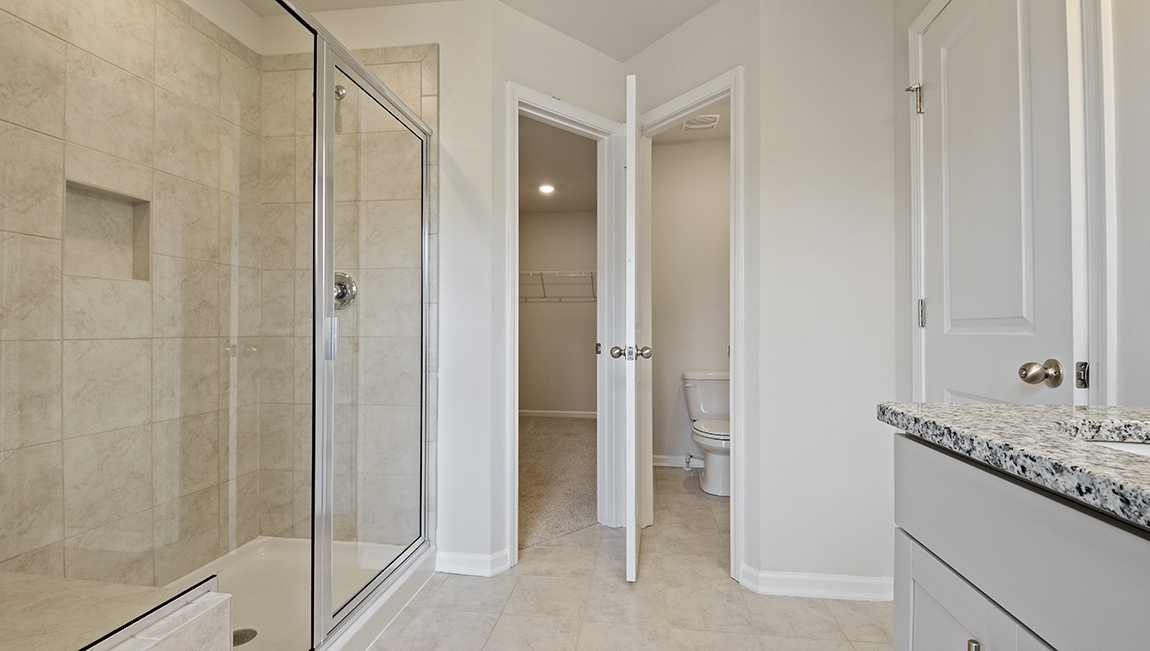 Primary bathroom with double sink vanity, walk in shower and bench