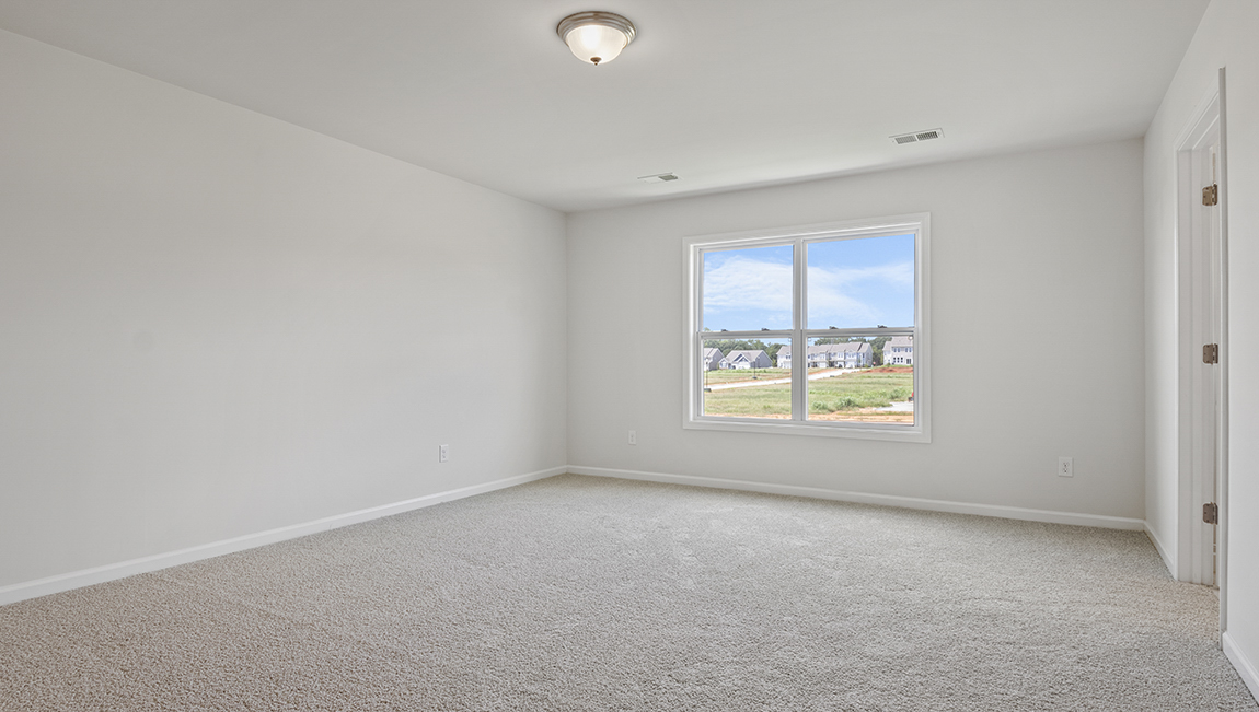 Primary carpeted bedroom with large windows
