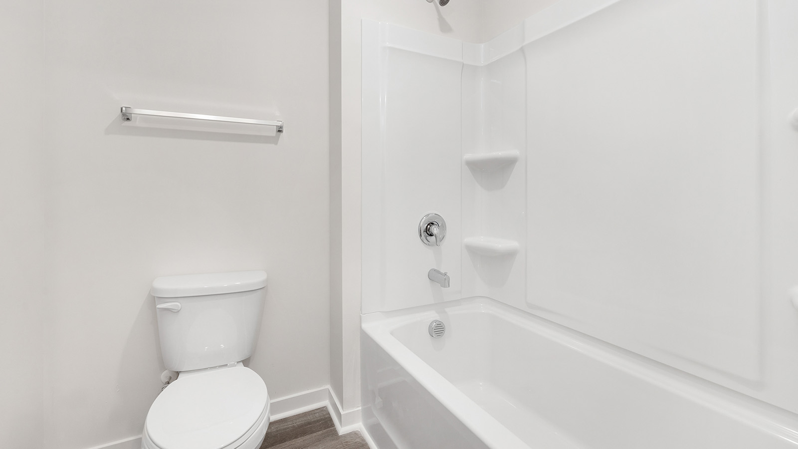 Model bathroom with white counters and cabinets, double sinks and glass door shower